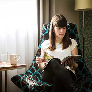 Signature room with a young lady sitting by the table reading a magazine