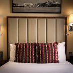 A small double room with a close up shot of the bed and red cushions