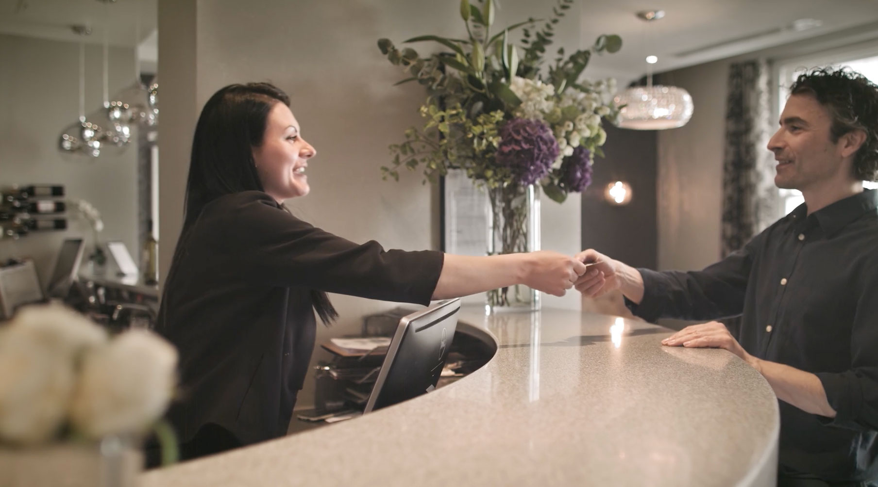 A staff member handing the key to new guest at the reception desk