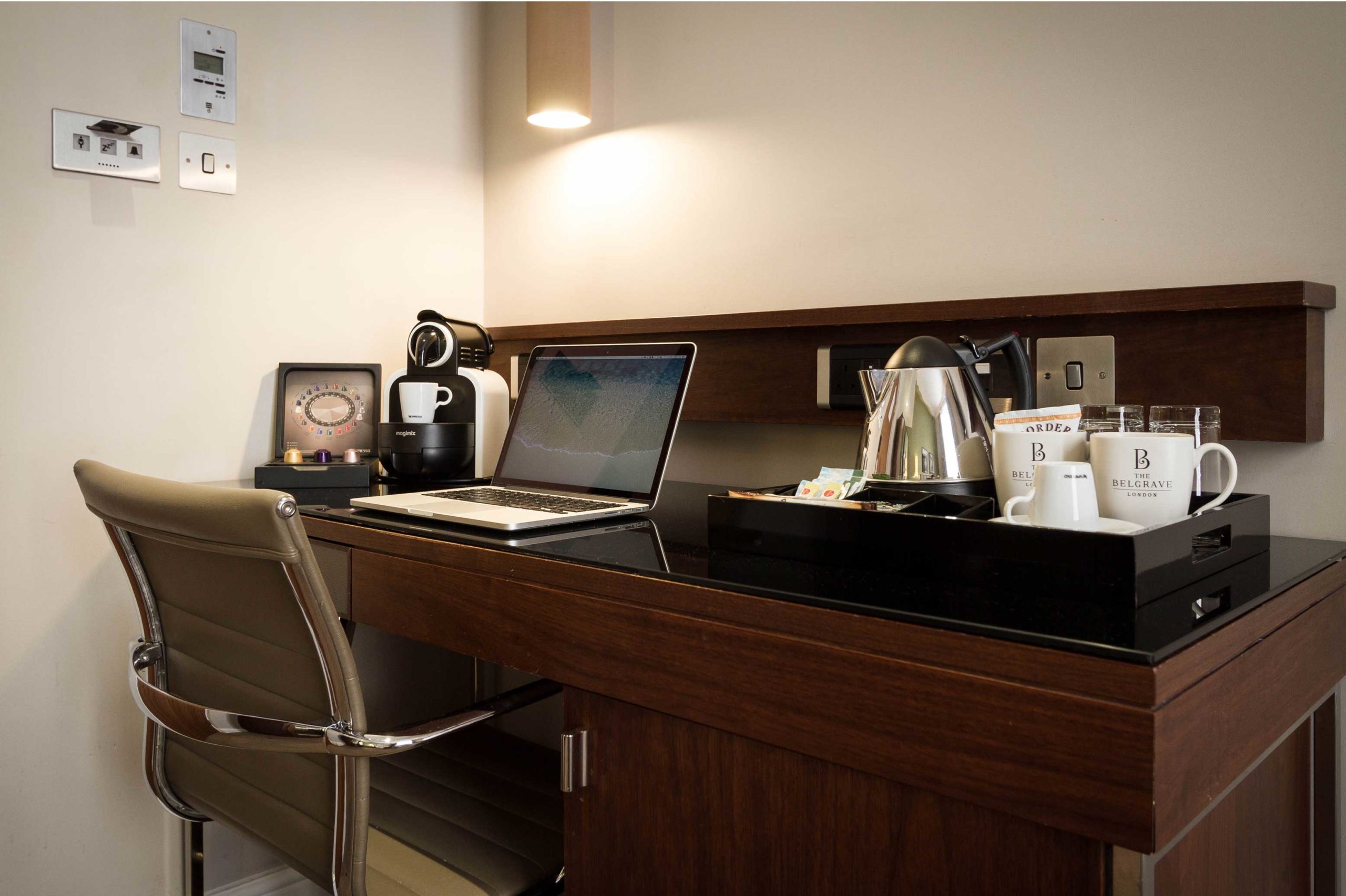 A desk area in the standard double room with a laptop and tea and coffee amenities