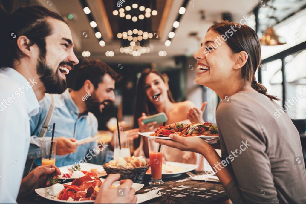 Four friends smiling and eating dinner