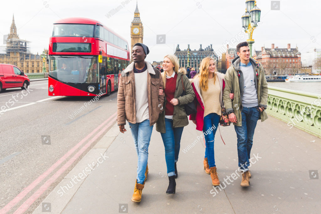 A group of 4 friends on a London bridge with a red bus and Big Ben behind them