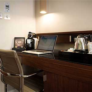 A desk area in the standard double room with a laptop and tea and coffee amenities