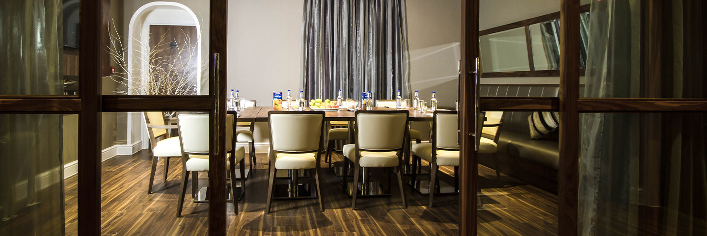 a long table with 6 chairs, A wooden sliding door is in front of the chairs.